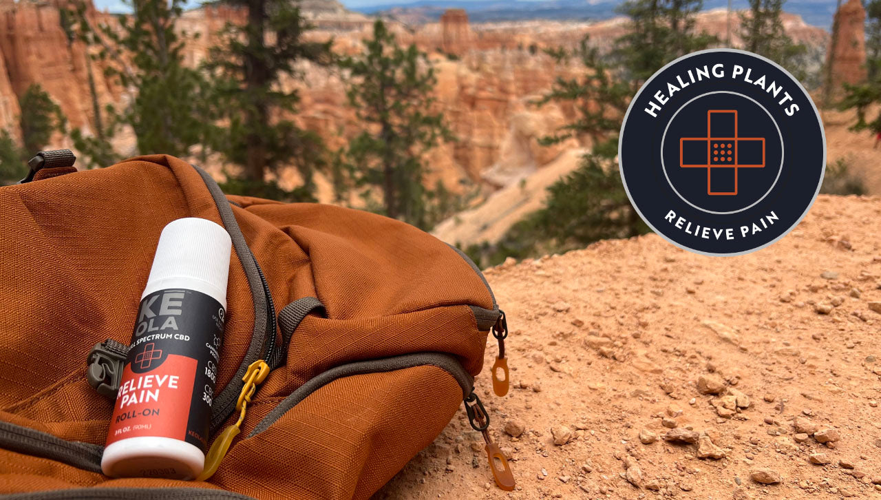 Keola Pain Relief Roll-On resting on a backpack on a mountain trail